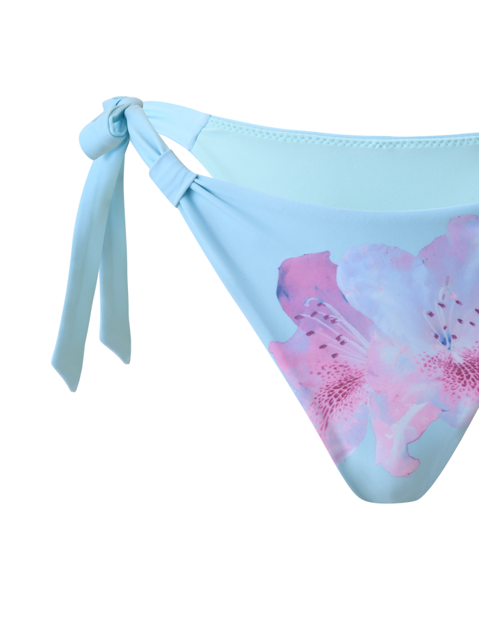 The TIGERMIST SID BIKINI BOTTOM - BLUE features adjustable left side ties and a bold pink and purple floral print on the right front, shown against a white background.