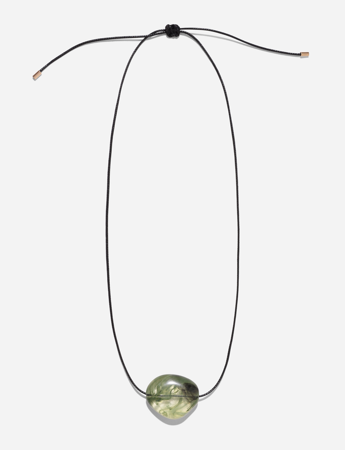 The SOLENE NECKLACE - GREEN by TIGERMIST features a minimalist black woven cord with an adjustable knot and a central oval translucent green stone pendant.