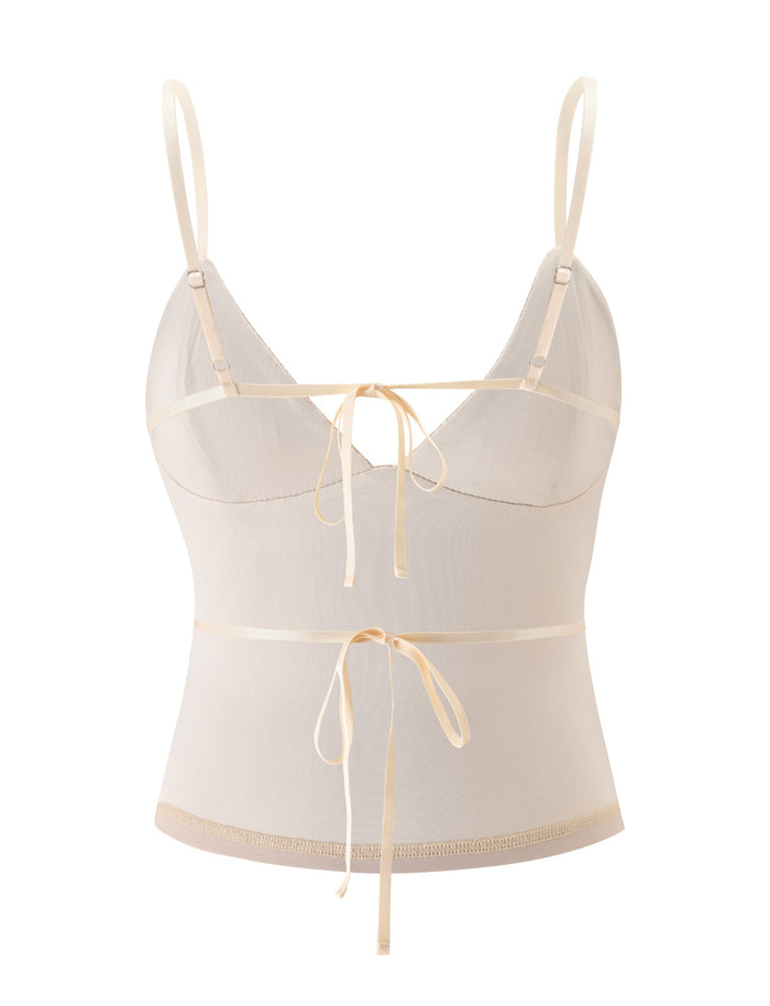 The SYLA TOP - OAT by TIGERMIST features a sheer ivory design with thin adjustable shoulder straps, satin ribbon accents at the bust and waist, and a fitted, slightly cropped silhouette—making it an essential addition to your summer wardrobe.