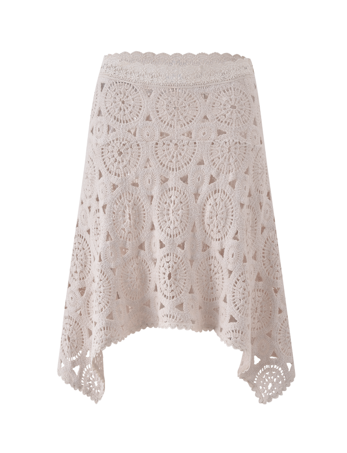 The TIGERMIST SYNTHIA CROCHET MIDI SKIRT in cream features a circular floral pattern, lace trim, and a scalloped handkerchief hem with an asymmetric cut. Shown against a plain white background.
