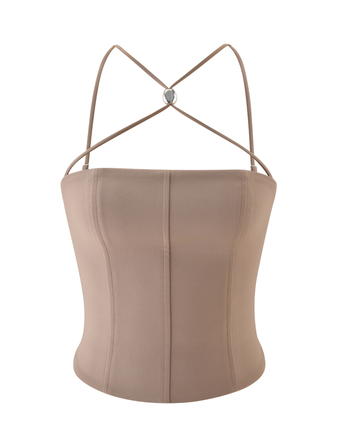 The TAMORA CORSET TOP by TIGERMIST is a taupe, 90's inspired sleeveless top with thin crisscross halter straps, a fitted structured design, and a circular metal detail at the back. The smooth fabric offers a slight stretch.