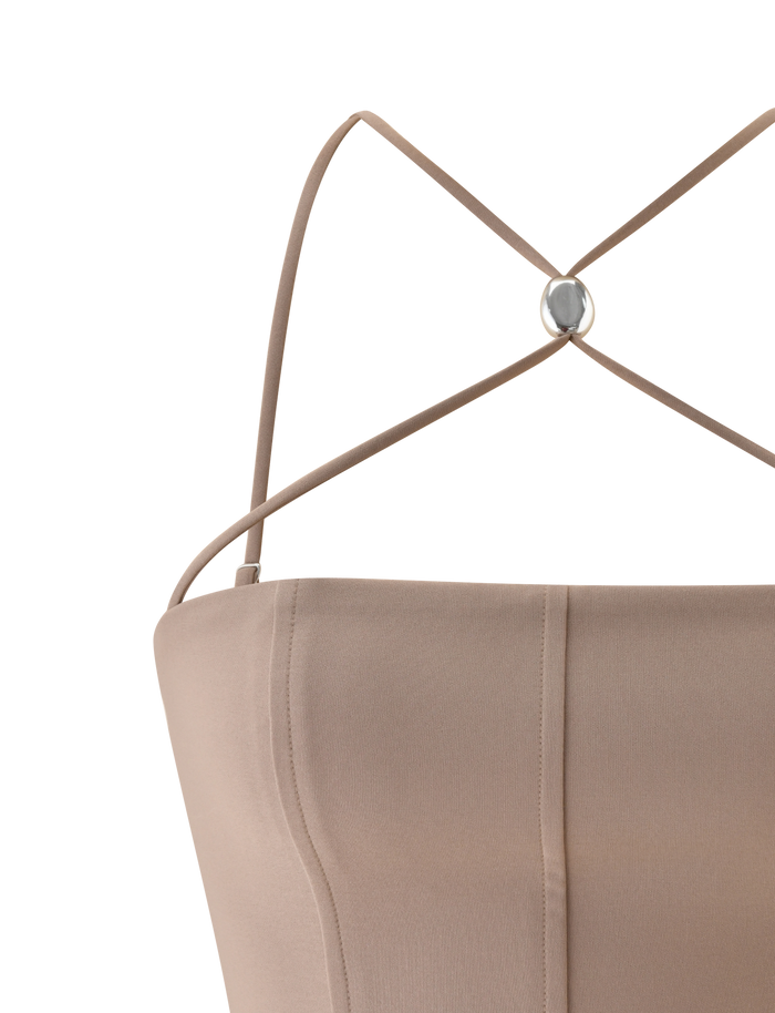 Close-up of the TIGERMIST TAMORA CORSET TOP in taupe, a 90's inspired style with thin adjustable crisscross straps meeting at a small round metallic accent on the back and visible seam details.