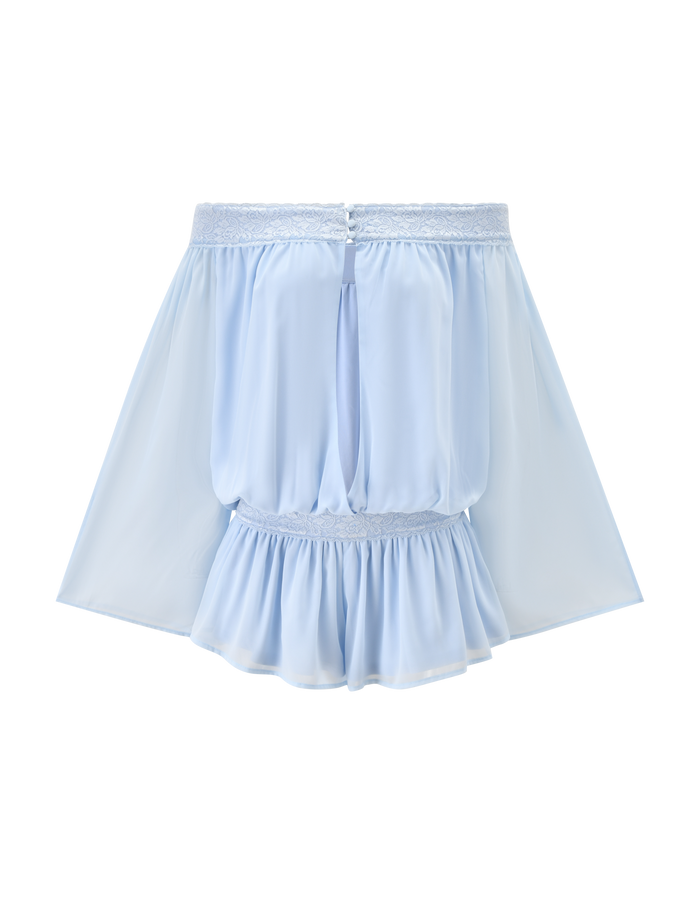 The TESSIE PLAYSUIT in baby blue by TIGERMIST features a sheer, high-waisted mini design with a lace trim waistband, gathered waist detail, and flared ruffled hem. Displayed on a plain white background.