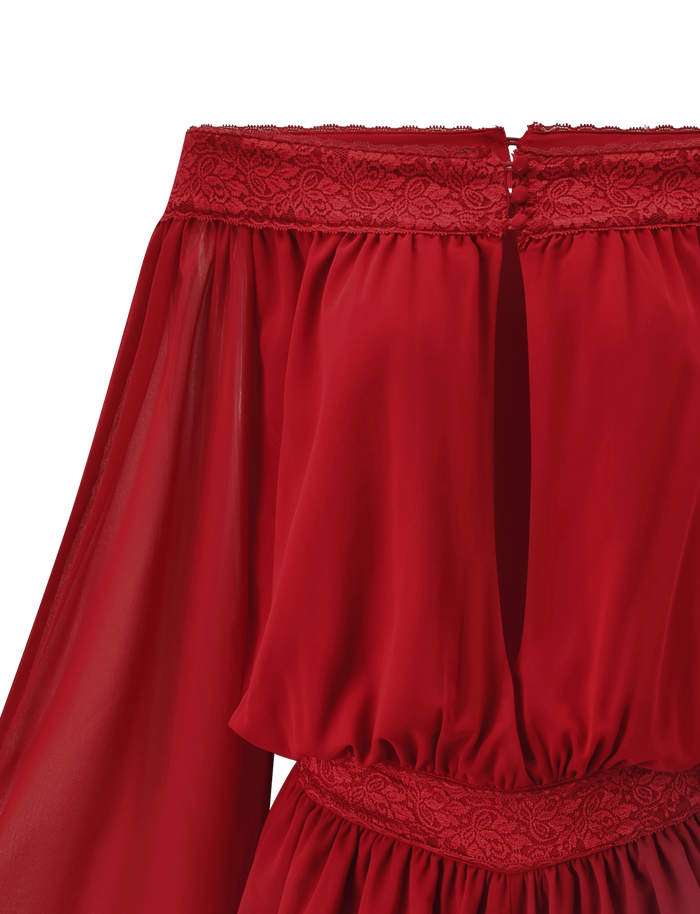 Close-up of the TESSIE PLAYSUIT in red by TIGERMIST, an off-shoulder romper with sheer long sleeves, lace trim at the neckline and waist, a front keyhole, and ruffled mini shorts for a playful finish.