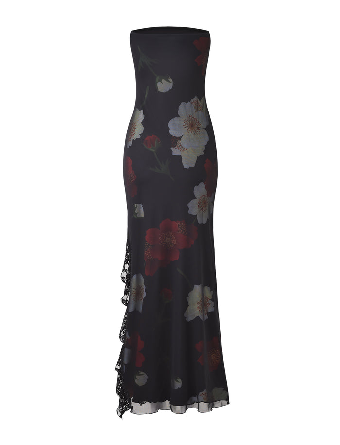 The Theo Maxi Dress - Red: Macro Floral by TIGERMIST is a strapless, floor-length black dress with a fitted silhouette. It features a striking red and white floral print and has a slight asymmetrical ruffle detail cascading down one side, adding an elegant touch.
