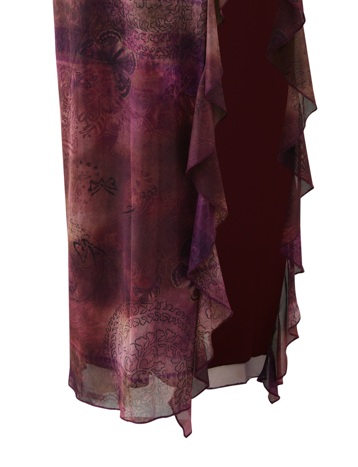 A close-up of TIGERMIST’s THEO SKIRT in Plum Butterfly Paisley, showing sheer purple and burgundy patterned fabric with waterfall ruffle edges and abstract floral motifs draped over a dark background.