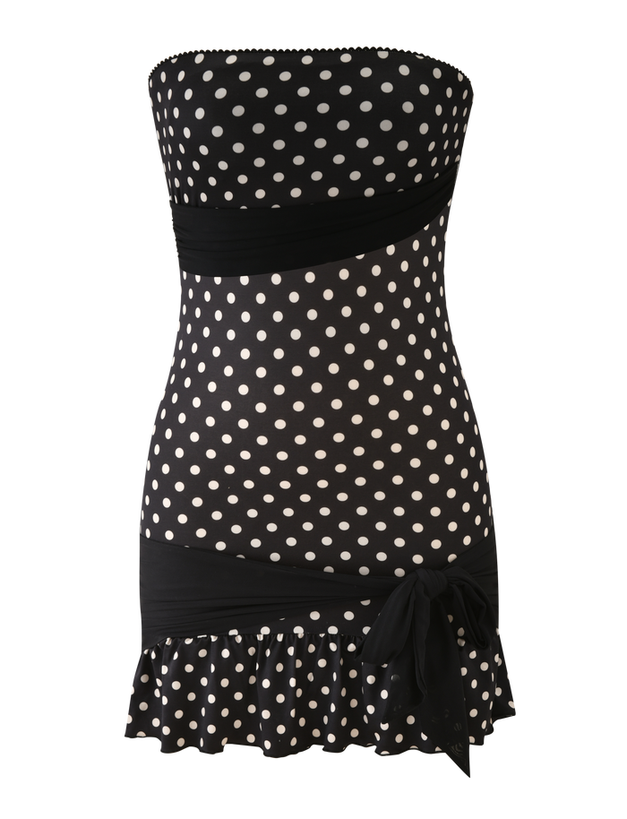 The TIGERMIST TOVE MINI DRESS in black polka dot is a strapless, bodycon mini dress featuring ruched waist and hem bands, a side bow detail, and a playful ruffle hem.
