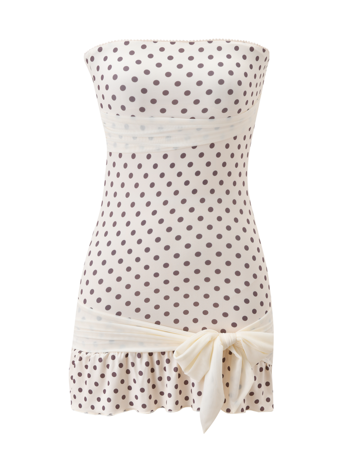 The TIGERMIST TOVE MINI DRESS in white polka dot features a strapless design, wide cream waistband, playful ruffle hem, and a large cream bow at the bottom.