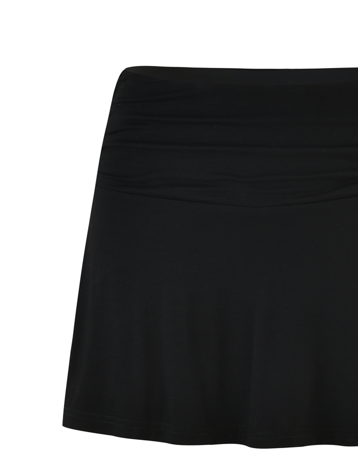 The VERITY SKORT - BLACK by TIGERMIST is a high-waisted, bodycon mini skort made from smooth, stretchy fabric, shown against a white background.