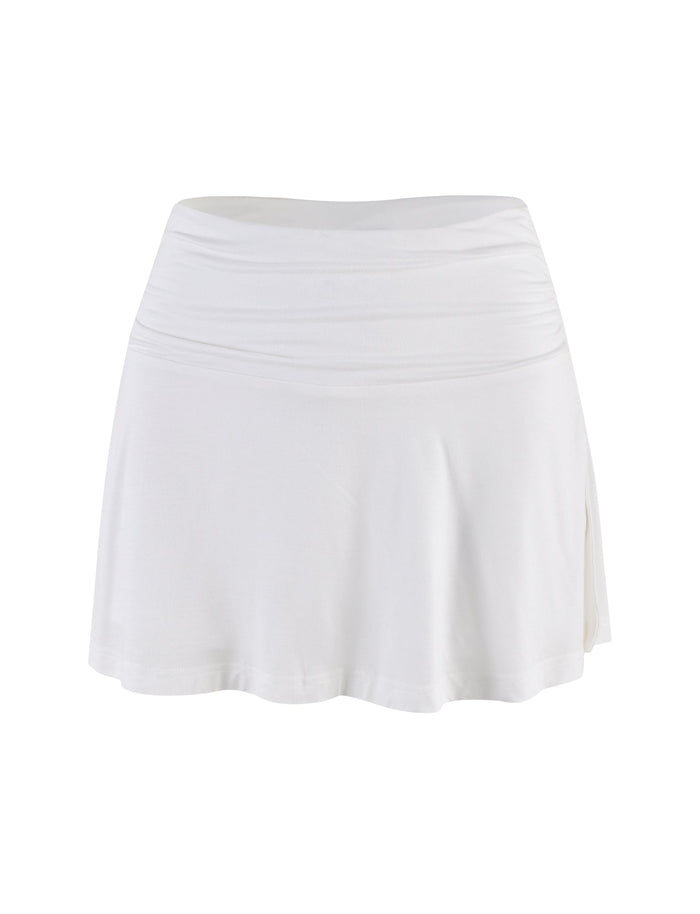 The VERITY SKORT by TIGERMIST is a white, knee-length A-line skort featuring a wide waistband and flattering low-rise fit, shown on a white background.