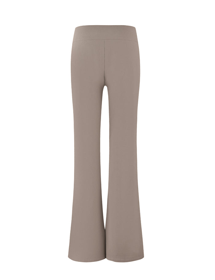Back view of the Vesper Pant in tan by TIGERMIST. These high-waisted flared pants feature a smooth texture and slightly widen from the knee down, creating a classic bell-bottom silhouette.