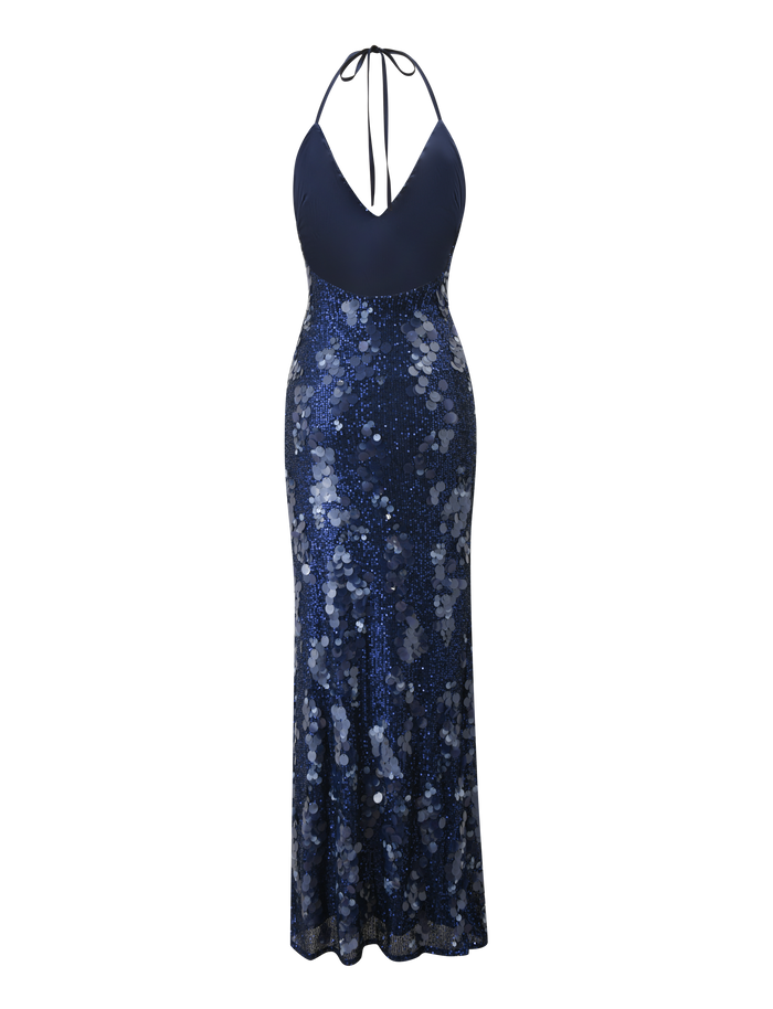 The ZANA MAXI DRESS - NAVY by TIGERMIST is a sleeveless sequin maxi dress with a plunging V-neck, halter tie, fitted silhouette, and a skirt shimmering in blue and silver tones.