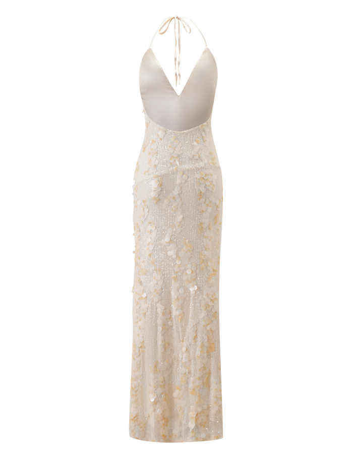 The ZANA MAXI DRESS - PEARL by TIGERMIST is a sleeveless, backless cream sequin dress featuring a plunging V-neckline, halter tie straps, and a sheer floor-length skirt with delicate sequin and floral embellishments.
