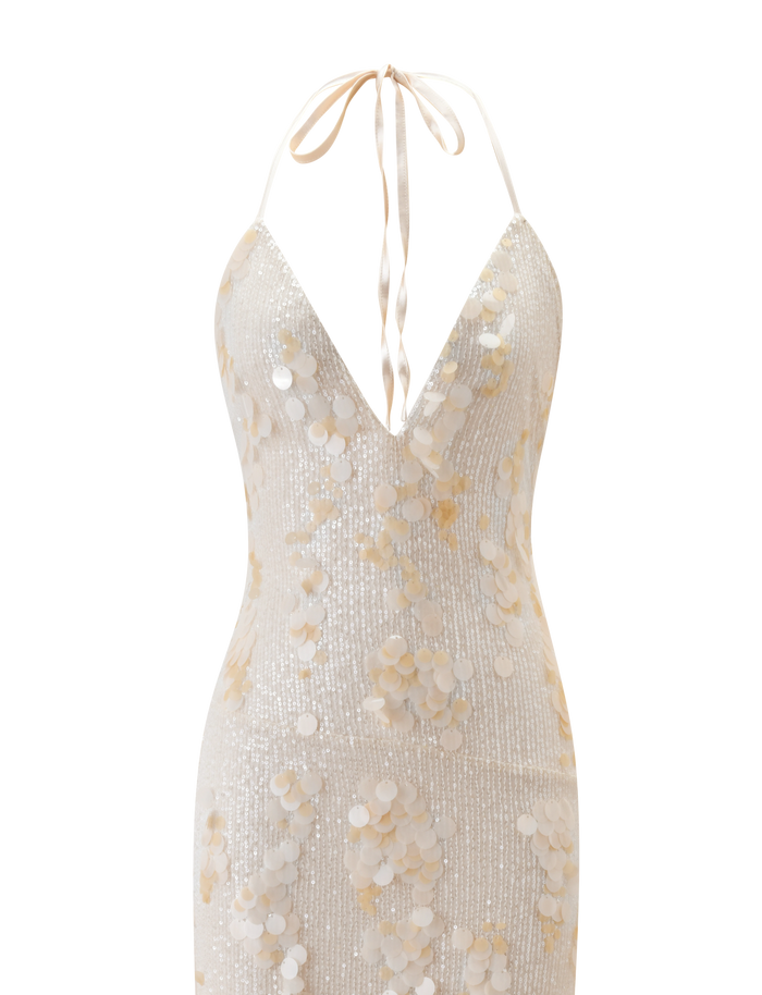 The ZANA MAXI DRESS - PEARL by TIGERMIST is a sleeveless, halter neck cream sequin maxi dress with a plunging V-neckline, neck tie, and large round pearl embellishments for a shimmery white or light beige textured look.