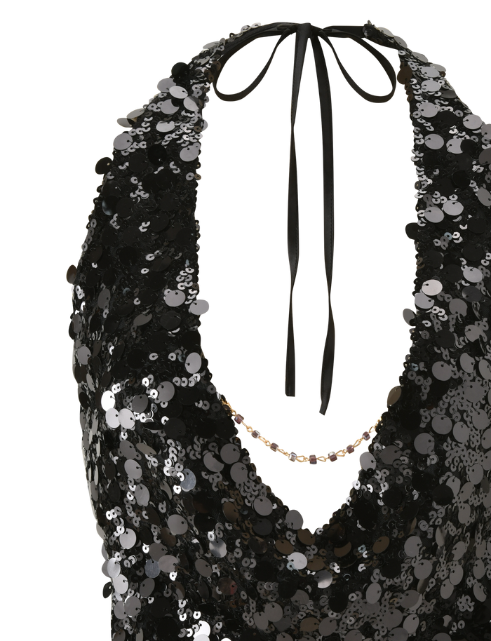A close-up of the TIGERMIST ZANA TOP - BLACK SEQUIN, a halter neck top adorned with shiny black and silver sequins, featuring a deep neckline and tie back.