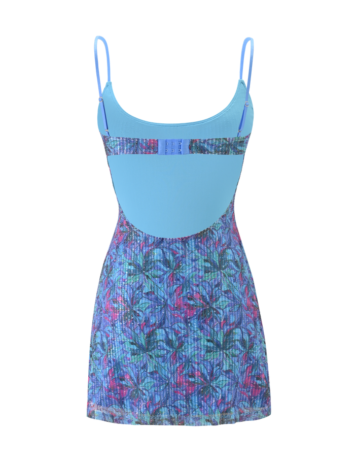 The ZEINA MINI DRESS by TIGERMIST features a sleeveless design with thin straps, a solid light blue bodice, and a floral sequin skirt in shades of blue, purple, and pink, shown against a plain background.
