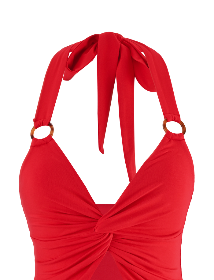 A close-up of the TIGERMIST ZENEVA TOP in red, featuring a halter neck, bust knot, twist detail, and tortoise shell ring accents on the straps, set against a white background.