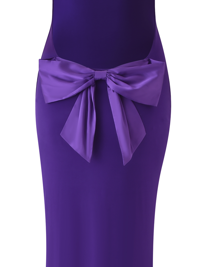 A close-up of the TIGERMIST ZITA MAXI DRESS in purple, showcasing a large matching fabric bow at the waist and a bodycon silhouette, set against a white background.